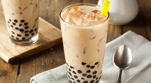Jak zrobić bubble tea? Pyszny napój z tapioką i lodem w szklance, z żółtą słomką.