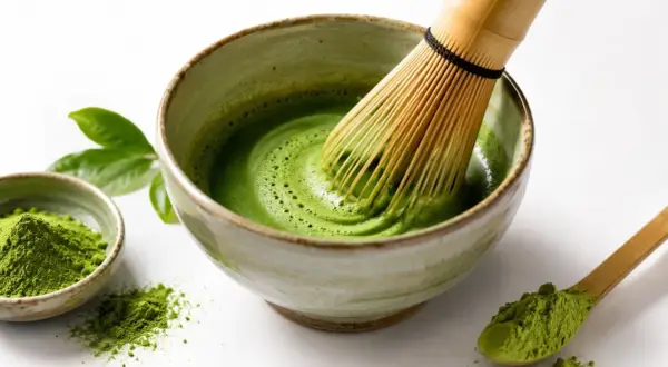 Tradycyjne przygotowanie napoju matcha. Bambusowa miotełka miesza zielony proszek z wodą w miseczce, tworząc piankę.