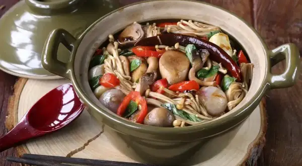 Aromatyczne danie z grzybkami mun, papryczką chili i innymi warzywami w glinianym garnku.