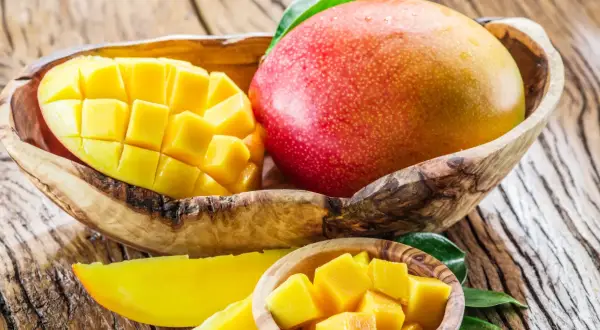 Słodkie, soczyste mango w drewnianej misce. Idealne na codzienne jedzenie mango, pełne witamin i słońca.