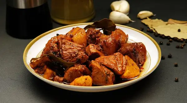 Talerz pełen mięsa w sosie, z dodatkiem czosnku, liści laurowych i pieprzu. To danie, które z pewnością wzbogaci smak dzięki przyprawie adobo.