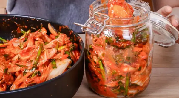 Przygotowanie domowego kimchi. W misce i słoiku widać warzywa z czerwoną pastą, kluczowe przyprawy do kimchi.