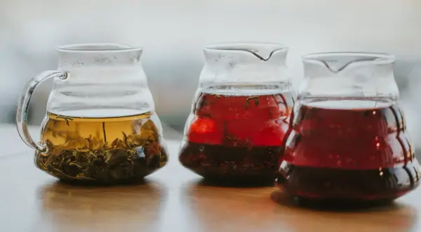 Trzy szklane dzbanki z naparami. Jeden z zieloną herbatą, bogatą w katechiny, dwa z czerwonymi napojami.