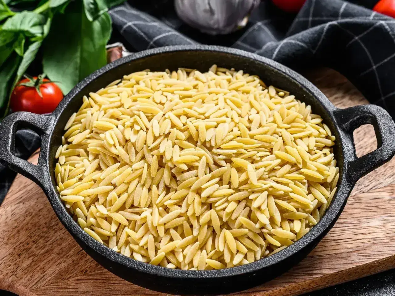 Miseczka pełna złotego makaronu ryżowego orzo, gotowego na pyszne danie.