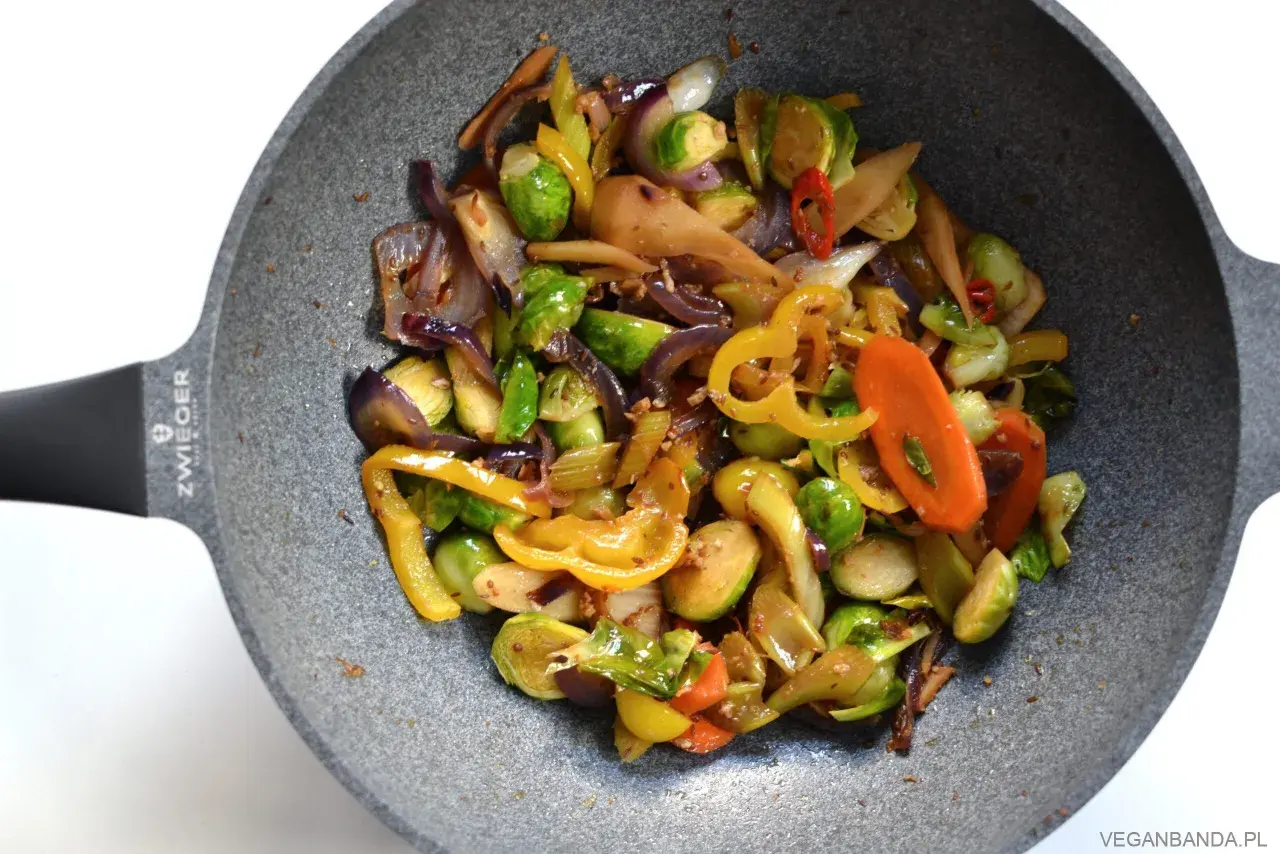 Kolorowe warzywa stir fry z brukselką, papryką i marchewką na patelni.
