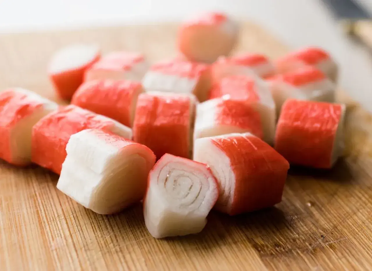 Pokrojone paluszki surimi na desce. Idealne do sałatek i przekąsek.