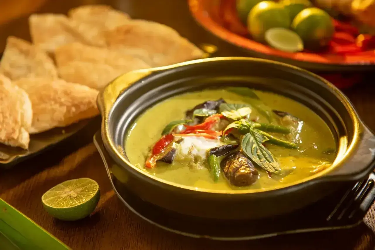 Aksamitne tajskie curry z mlekiem kokosowym, pełne warzyw i ziół, podane z chrupiącym pieczywem i limonką.