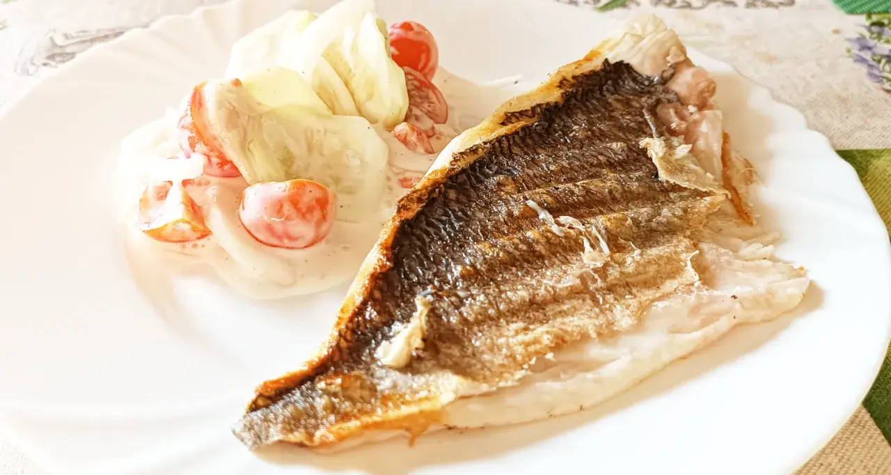 Dorada grillowana z chrupiącą skórką, podana z orzeźwiającą sałatką z pomidorków i ogórka w sosie.