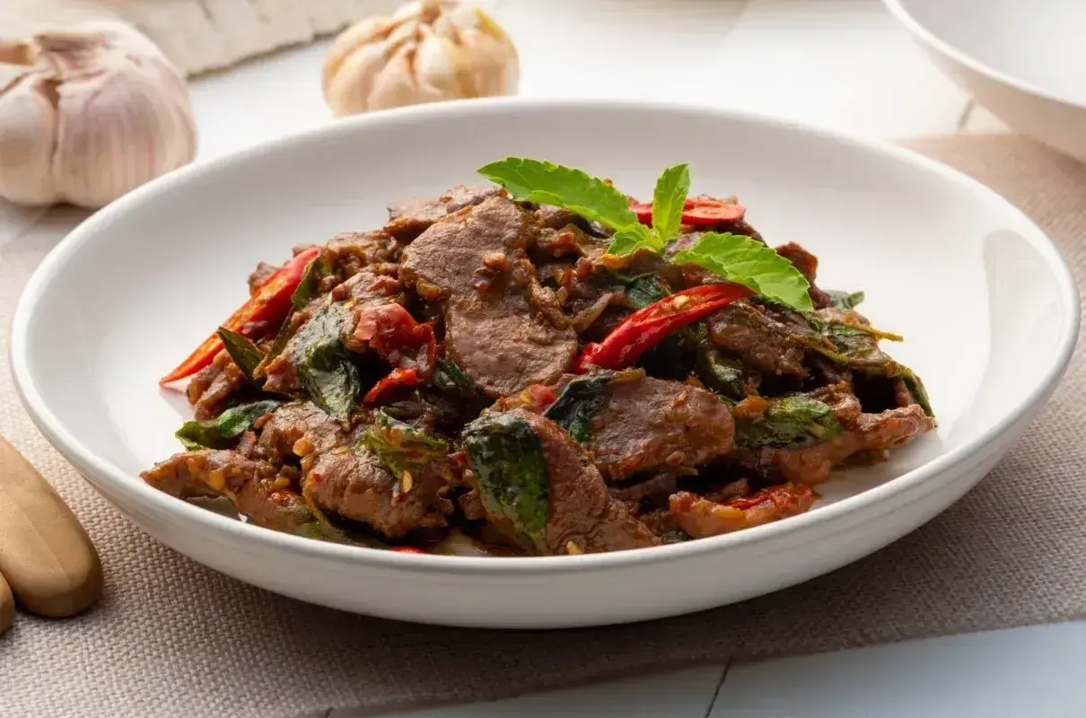 Wołowina po azjatycku z bazylią i papryczką chili, podana w białej misce.