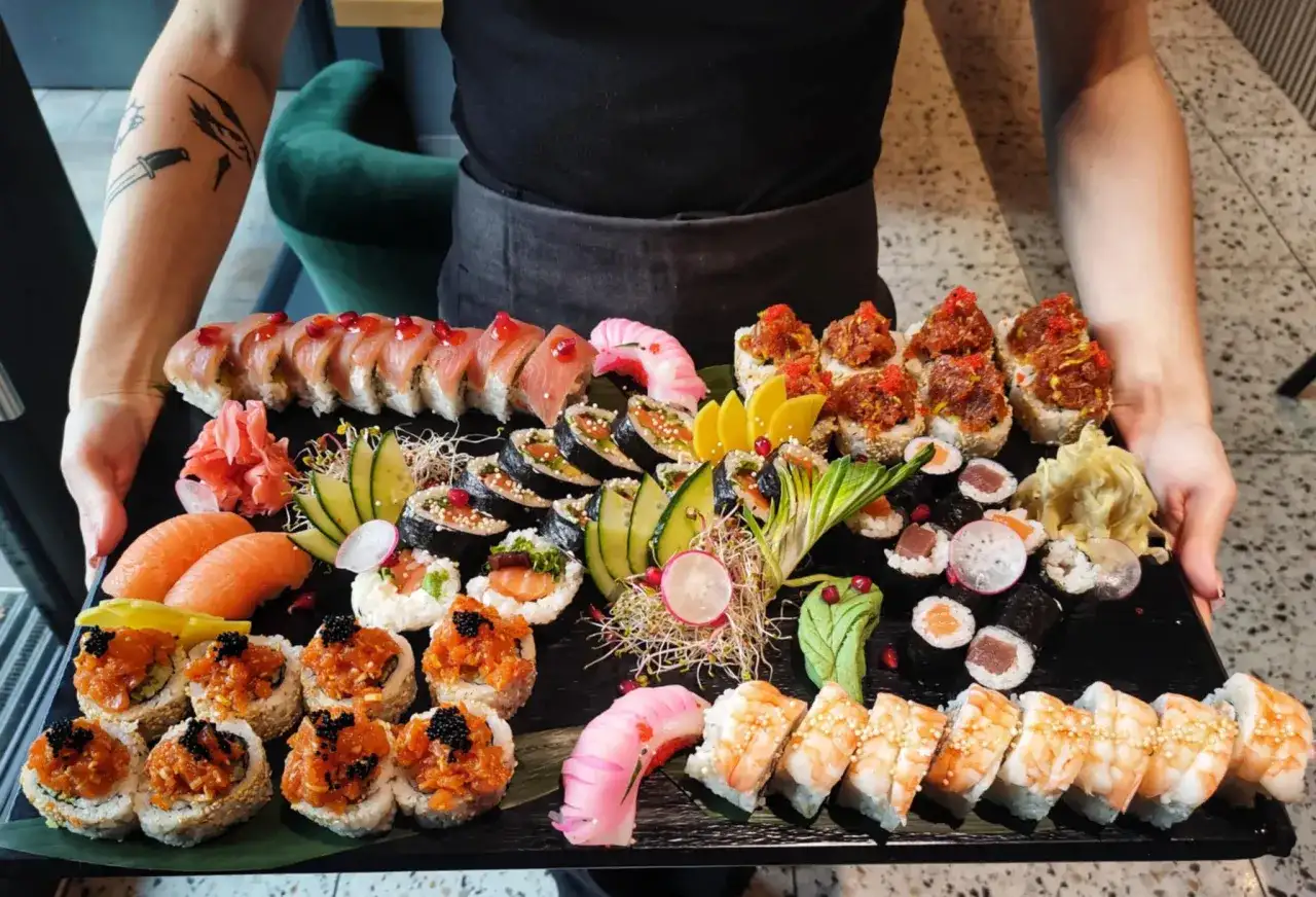 Taca pełna sushi, idealna do nauki, jak jeść sushi. Różne rodzaje rolek, nigiri z łososiem, krewetki i dodatki.