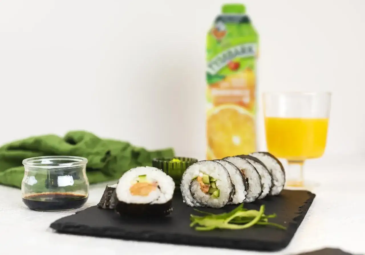 Pyszne sushi z łososiem, ogórkiem i ryżem, podane z sosem sojowym i sokiem pomarańczowym. Idealne na lekki posiłek.