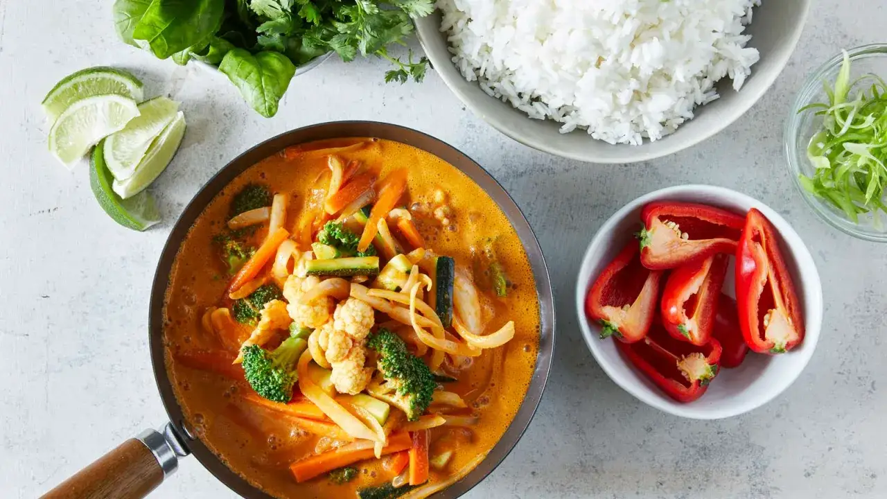 Aksamitny, aromatyczny thai red curry z warzywami: brokułami, marchewką, cukinią i kalafiorem, podany z ryżem.