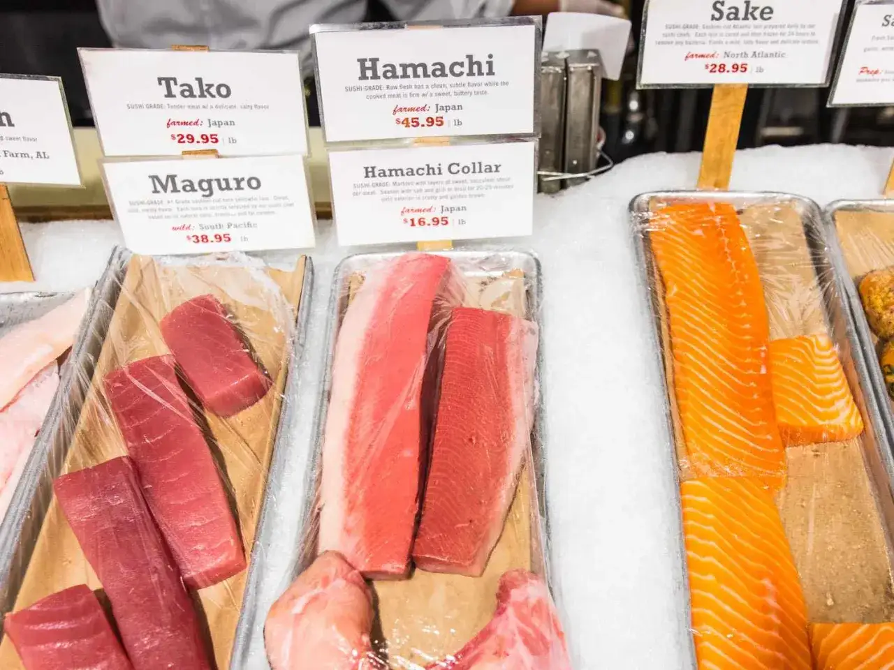 Jaki łosoś do sushi? Jasny, pomarańczowy łosoś w plastrach, idealny na sushi, leży obok tuńczyka i innych ryb.