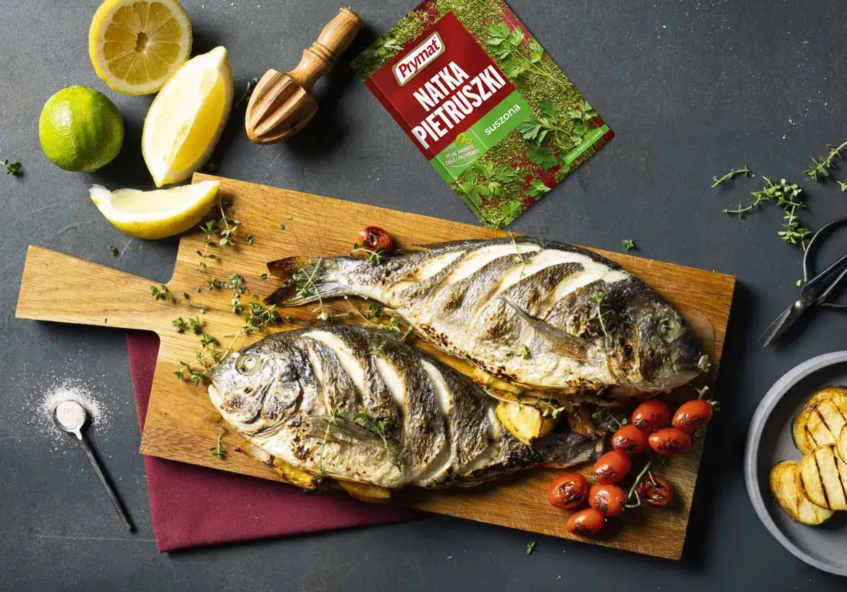 Dorada grillowana z cytryną i pomidorkami, doprawiona natką pietruszki.