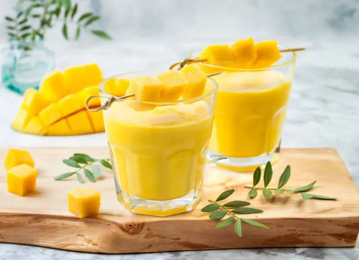 Dwa szklanki gęstego, żółtego napoju z kawałkami mango na patyczku. To właśnie lassi, orzeźwiający napój jogurtowy.