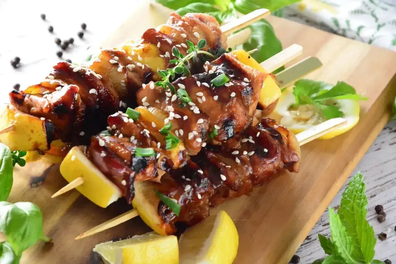 Pyszne szaszłyki yakitori z kurczaka w sosie teriyaki, posypane sezamem i szczypiorkiem. Idealne na grilla, oto prosty yakitori przepis.