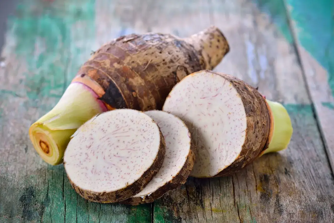 Taro, czyli bulwa o brązowej skórce i jasnym, nakrapianym miąższu, pokrojona w plastry.