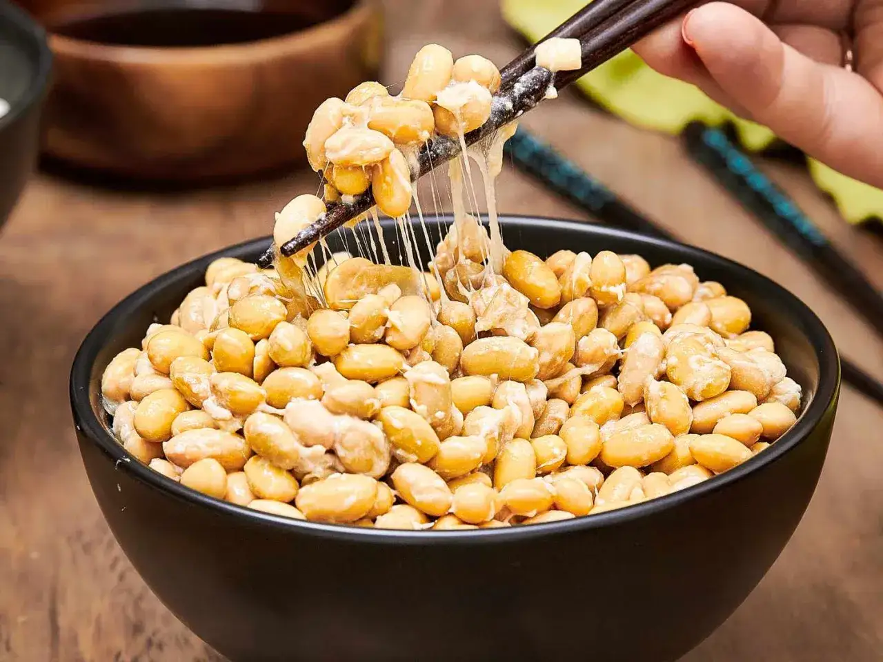 Misternie lepkie ziarna soi, czyli natto, podnoszone pałeczkami z czarnej miski. Zastanawiasz się natto co to? To tradycyjna japońska potrawa.