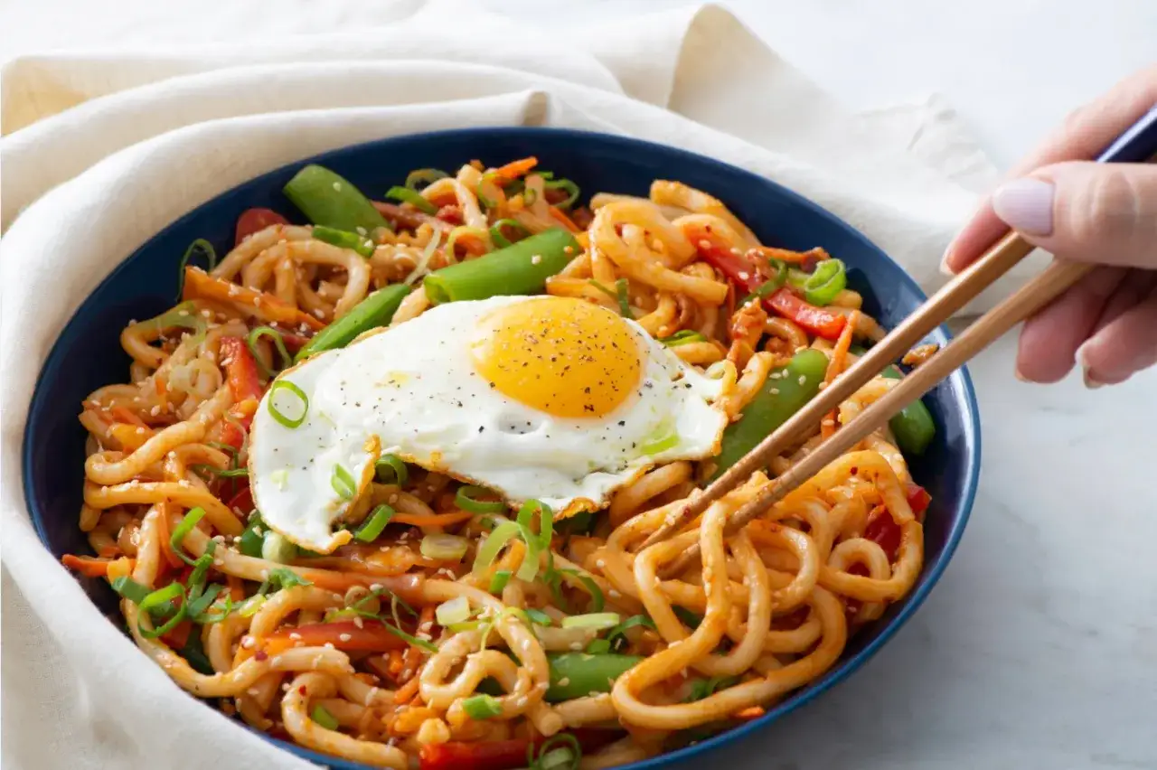 Miseczka makaronu udon z jajkiem sadzonym i warzywami. Pyszne danie, które nie musi mieć wielu kcal.