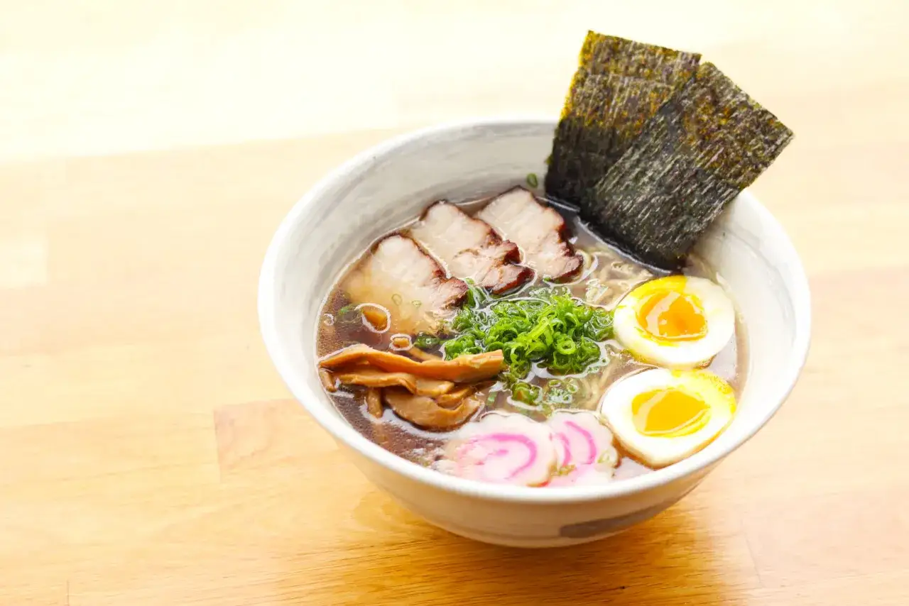 A miseczce shoyu ramen z plastrami wieprzowiny, jajkami na pół, bambusem i wodorostami nori.
