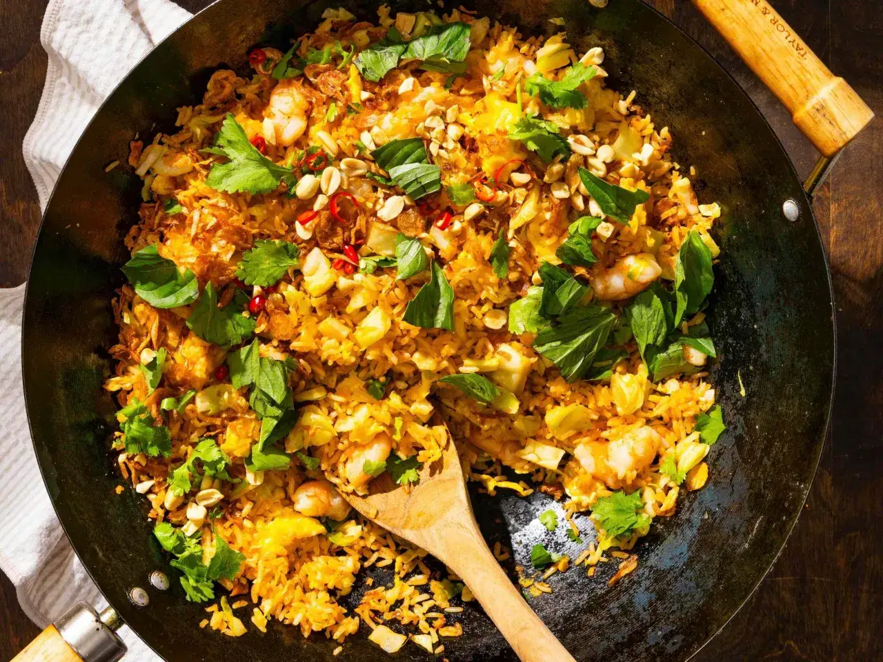 Pyszne krewetki z ryżem w woku, posypane orzeszkami ziemnymi, chili i świeżą kolendrą. Idealne danie dla miłośników azjatyckich smaków.