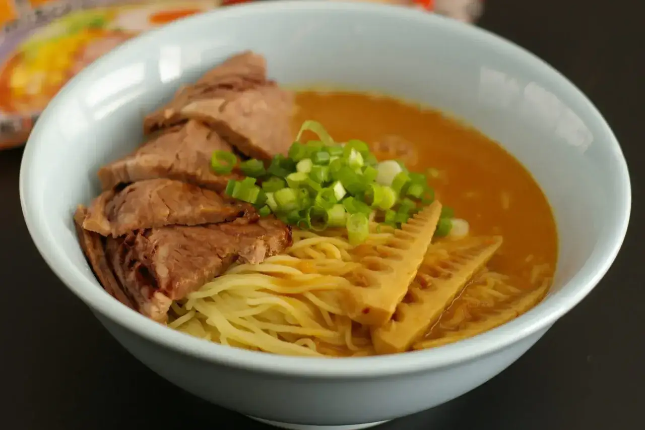 Miseczka aromatycznego menma ramen z plastrami mięsa, makaronem, bambusem i szczypiorkiem.