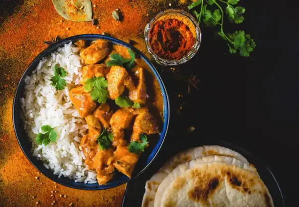 Aksamitny butter chicken, przepis oryginalny, podany z ryżem i chlebkiem naan. Aromatyczne przyprawy dopełniają danie.