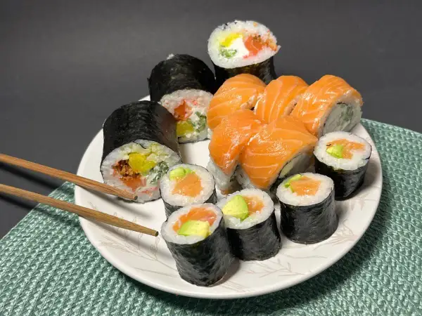 Talerz pełen sushi z łososiem i awokado. Wśród nich rolka z kremowym serkiem do sushi, która dodaje im wyjątkowego smaku.