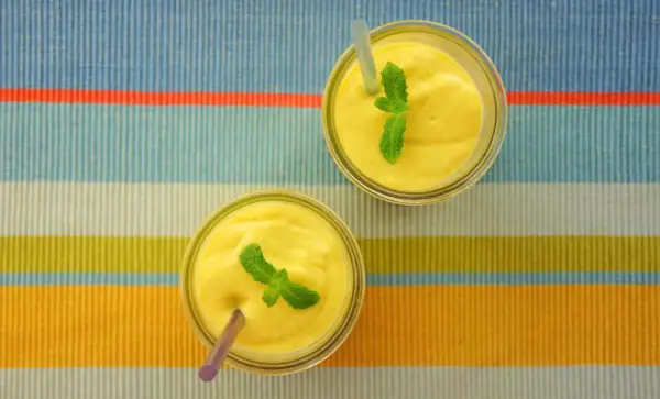 Dwa pyszne mango lassi, orzeźwiające napoje z Indii, ozdobione listkami mięty, czekają na spróbowanie.