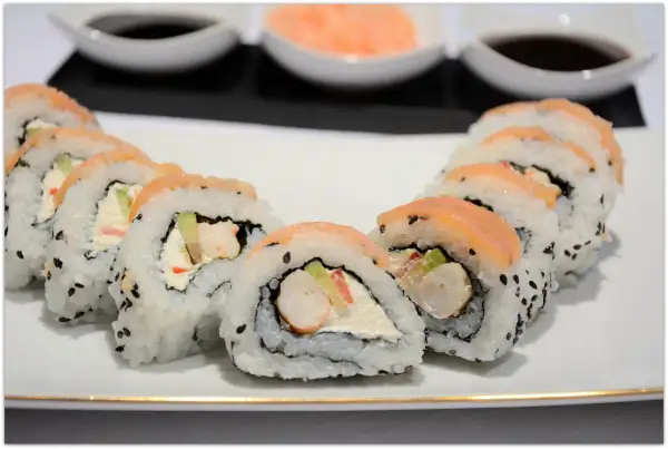 Pyszne rolki sushi z łososiem i kremowym serkiem, w środku widoczne kawałki krewetek do sushi.