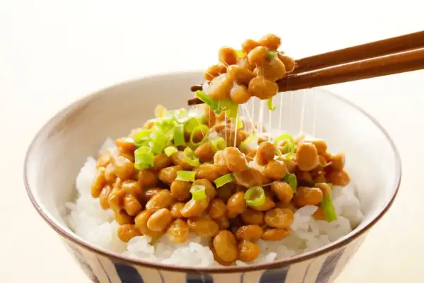 Misternie lepkie ziarna natto, posypane szczypiorkiem, unoszą się nad miską ryżu. To właśnie natto, tradycyjne japońskie danie.