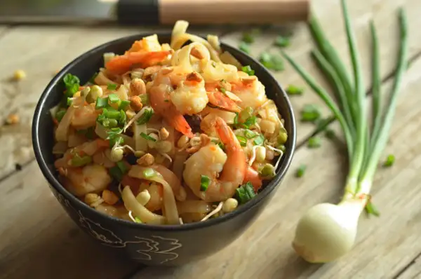 Miseczka pełna krewetek, makaronu ryżowego, kiełków fasoli mung i szczypiorku. To wygląda jak pad thai oryginalny przepis.