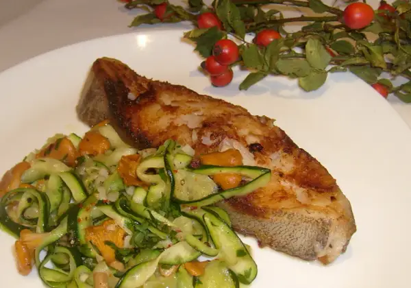 Złocisty halibut stek z chrupiącą skórką, podany z sałatką z cukinii i kurkami.