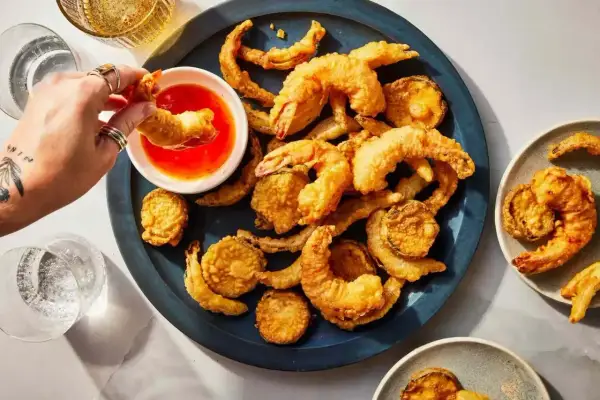 Chrupiące krewetki i warzywa w cieście tempura, zanurzane w sosie. Idealny składnik na przekąskę.