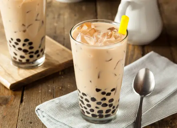 Jak zrobić bubble tea? Pyszny napój z tapioką i lodem w szklance, z żółtą słomką.