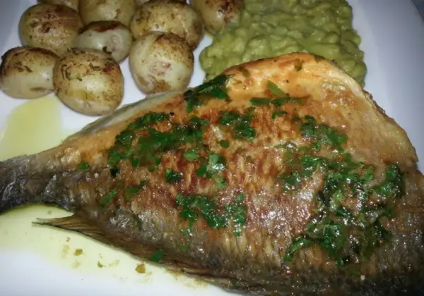Usmażona ryba bass z ziołami, podana z pieczonymi ziemniaczkami i zielonym puree.