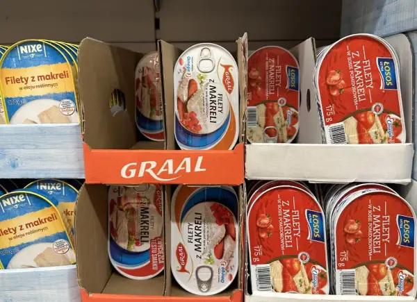 Półka sklepowa z różnymi rodzajami ryb w puszce: filety z makreli w oleju roślinnym i w sosie pomidorowym.