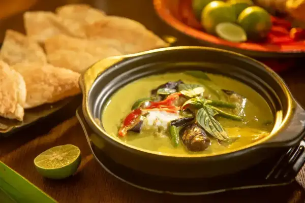 Aksamitne tajskie curry z mlekiem kokosowym, pełne warzyw i ziół, podane z chrupiącym pieczywem i limonką.