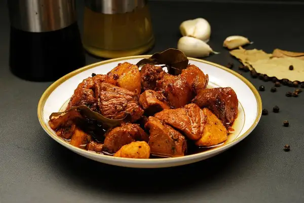 Talerz pełen mięsa w sosie, z dodatkiem czosnku, liści laurowych i pieprzu. To danie, które z pewnością wzbogaci smak dzięki przyprawie adobo.