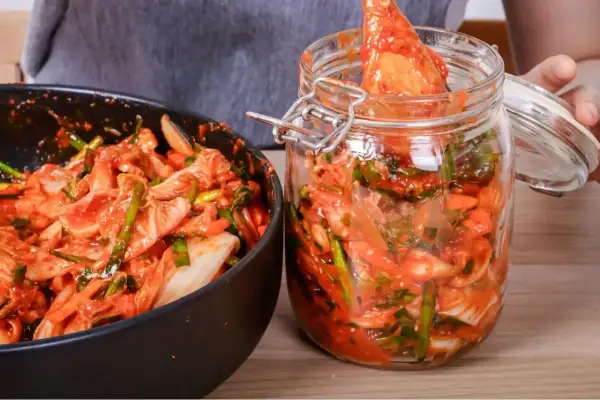 Przygotowanie domowego kimchi. W misce i słoiku widać warzywa z czerwoną pastą, kluczowe przyprawy do kimchi.